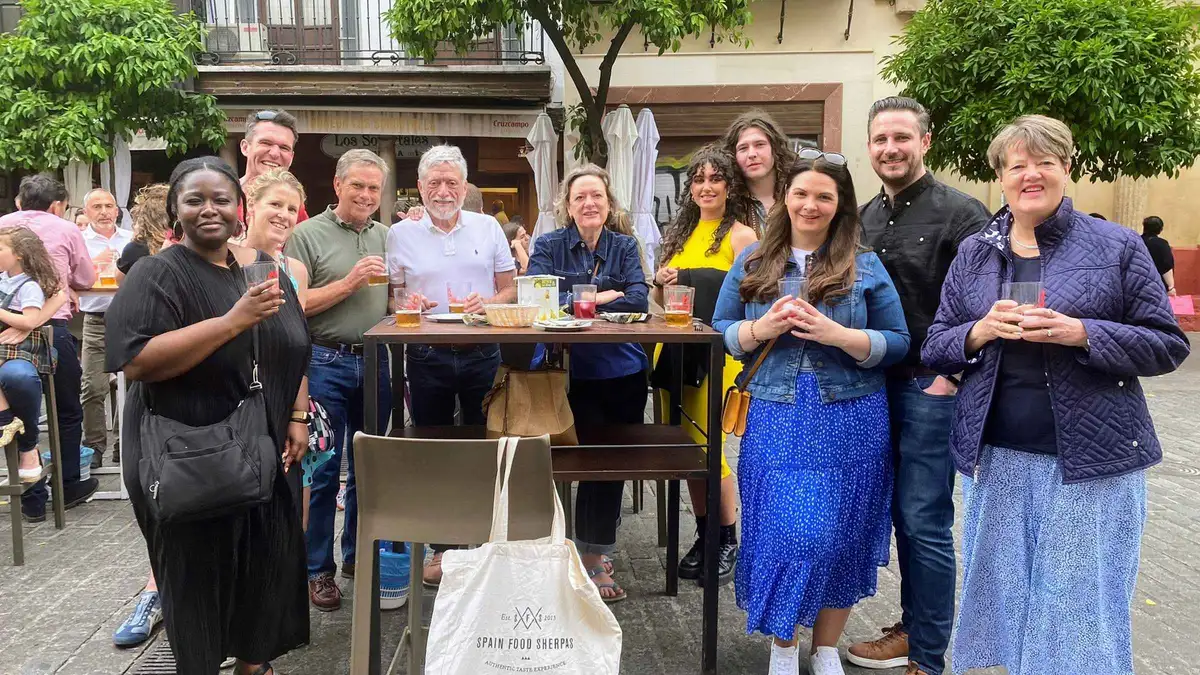 Guide serving flaming chorizo and vermouth in a century-old tavern on a Seville food tour of historic taverns